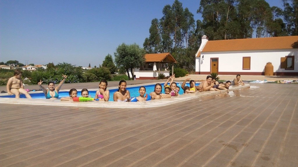 Crianças e monitores a divertir-se na piscina no programa de férias